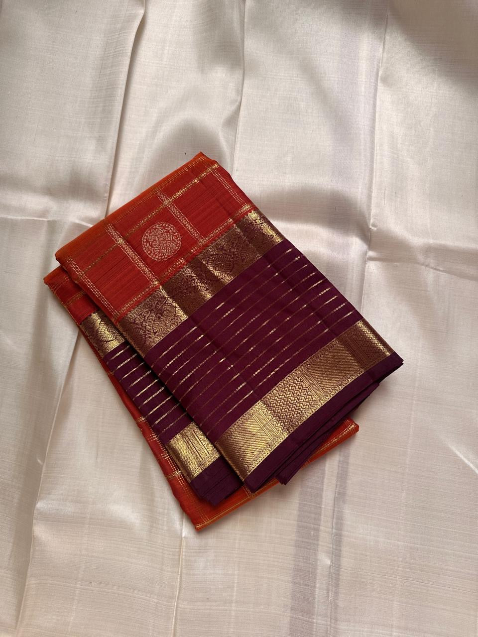 Cinnamon Kattam – Pure Kanchipuram Silk Saree
Vermillion red body with gold kattam checks & floral buttas
Contrast plum purple korvai borders with rich zari weave
Grand zari pallu with lattice & floral motifs in gold
Silk Mark Certified ships in 2weeks