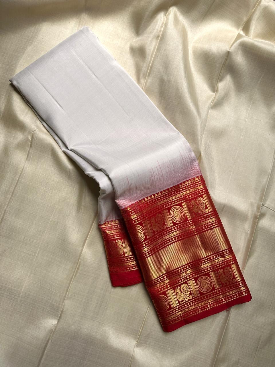 A true festival essential white with dashing red pure silk Kanchipuram saree with a kamalam and mayil detailed border zari work , red reku and Pallu