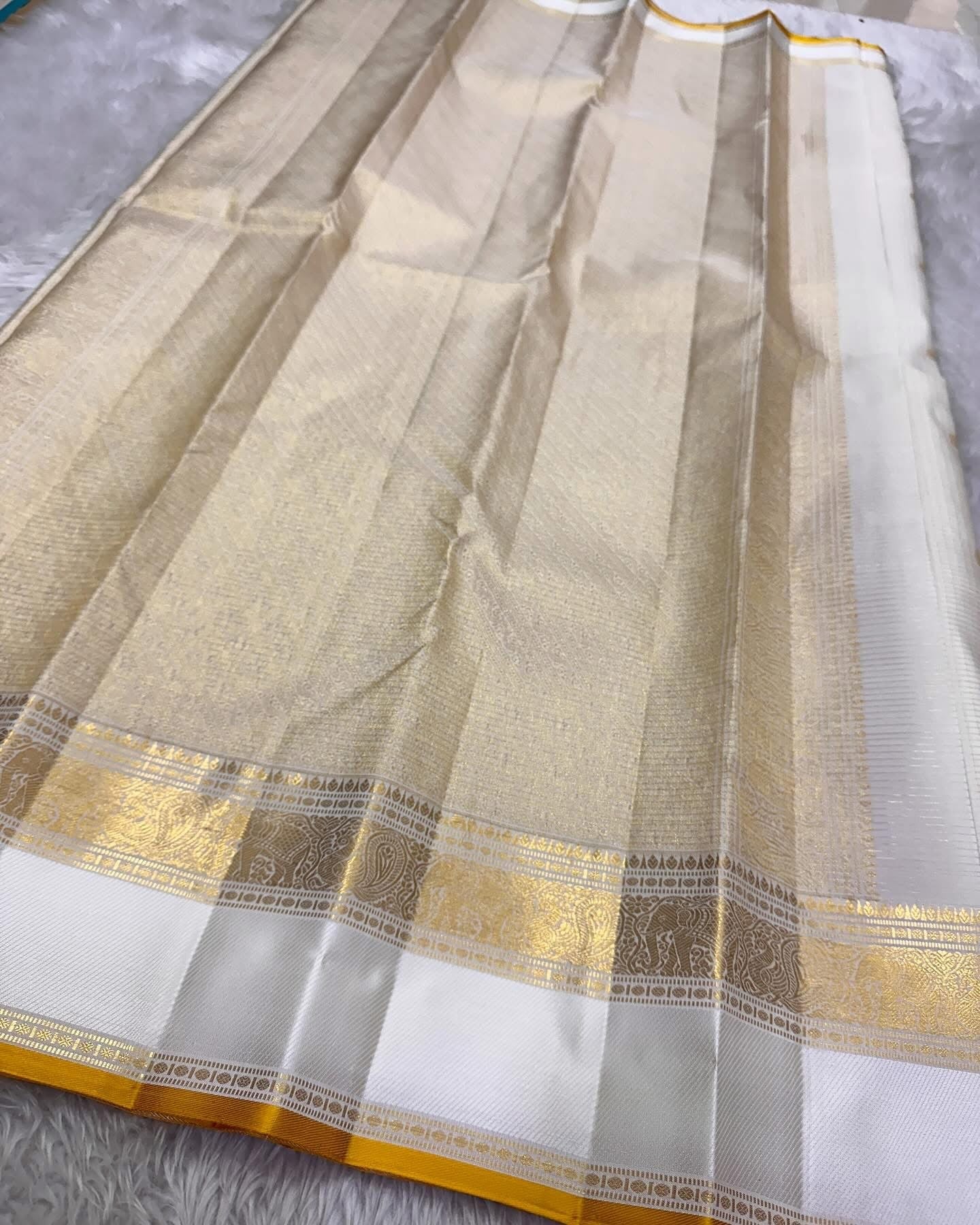 Kiran ivory whiteb oosi kattam ✨ – ivory and gold Kanchipuram Pure Silk Saree
Korvai Gold Zari Border with Elephant & Floral Motifs
Body Woven in Zari Kattam Checks with Scattered Gold Buttas
Grand Zari Brocade Pallu | Silk Mark Certified |