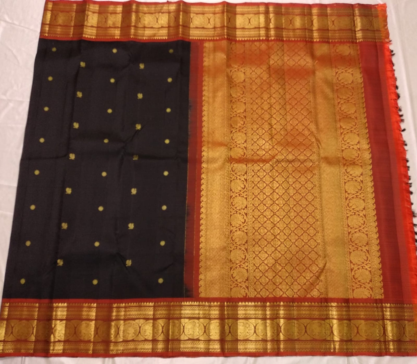Traditional saree with black, gold, and red patterns on a white background