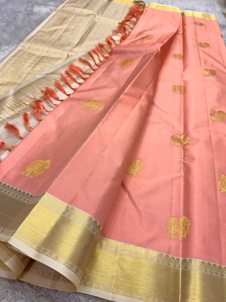Ivory Blush Meadow – Pure Kanchipuram Silk Saree
Blush-Peach Body with Gold Zari Animal Buttas
Ivory-Gold Contrast Border with Floral Motifs
Grand Ivory-Gold Brocade Pallu in Traditional Weave
Silk Mark Certified, delivery in 2 weeks