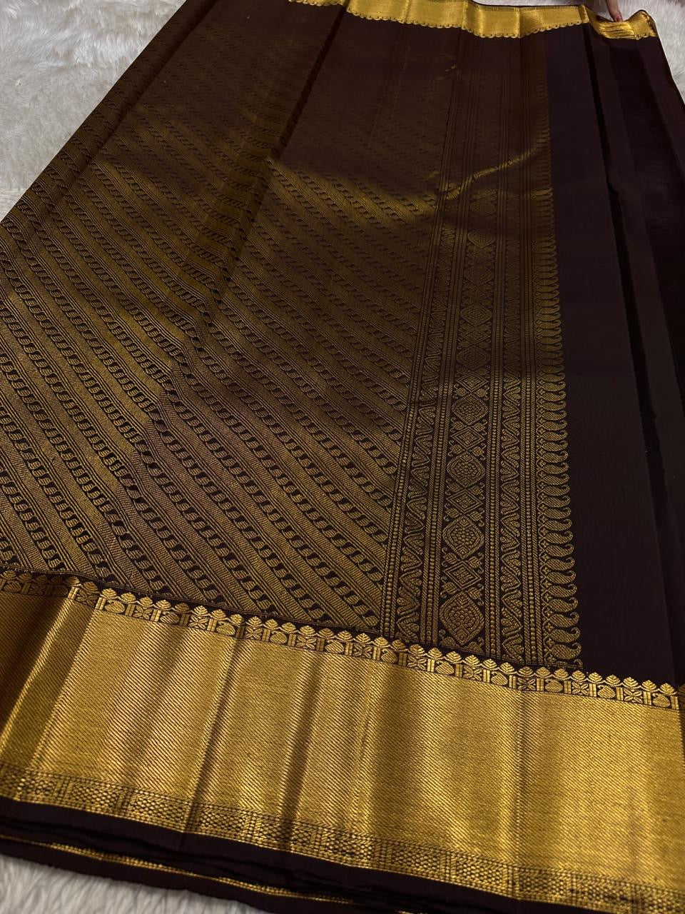 Agnika – Dark Espresso Kanchipuram Silk Saree with Mayil Chakram Butta
Fiery and regal, Agnika features a rich dark espresso silk body with intricate Mayil Chakram (peacock) motifs and a shimmering zari border—an elegant ode to South Indian tradition.