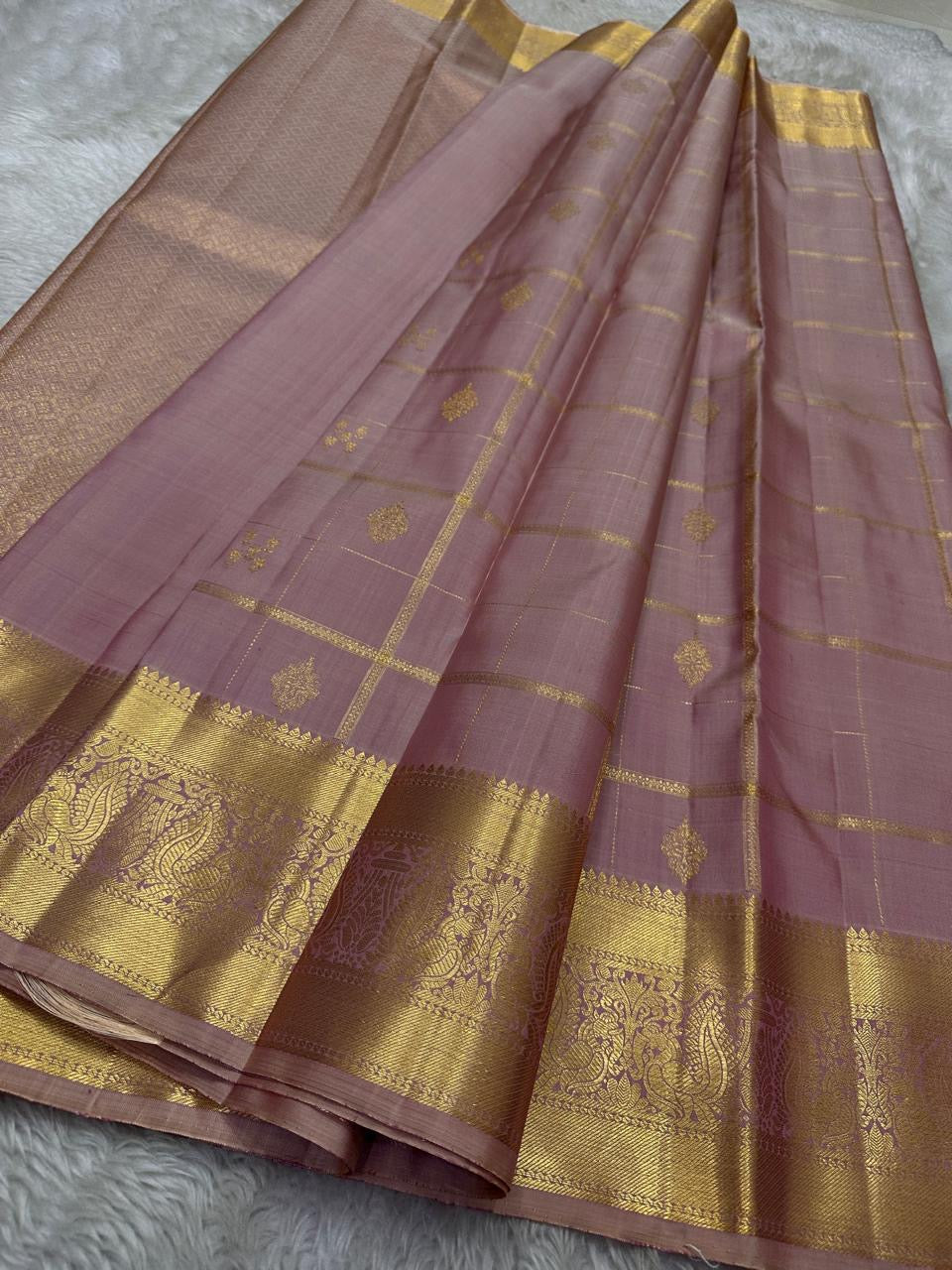 Lilac Mayil – Pure Kanchipuram Silk Saree
Ash-Lilac Body with Zari Kattam Checks & Buttas
Broad Antique-Gold Peacock Zari Borders
Grand zari Pallu
Silk Mark Certified | Fall & Pico Done | Blouse Stitching Available | ships in two weeks Free