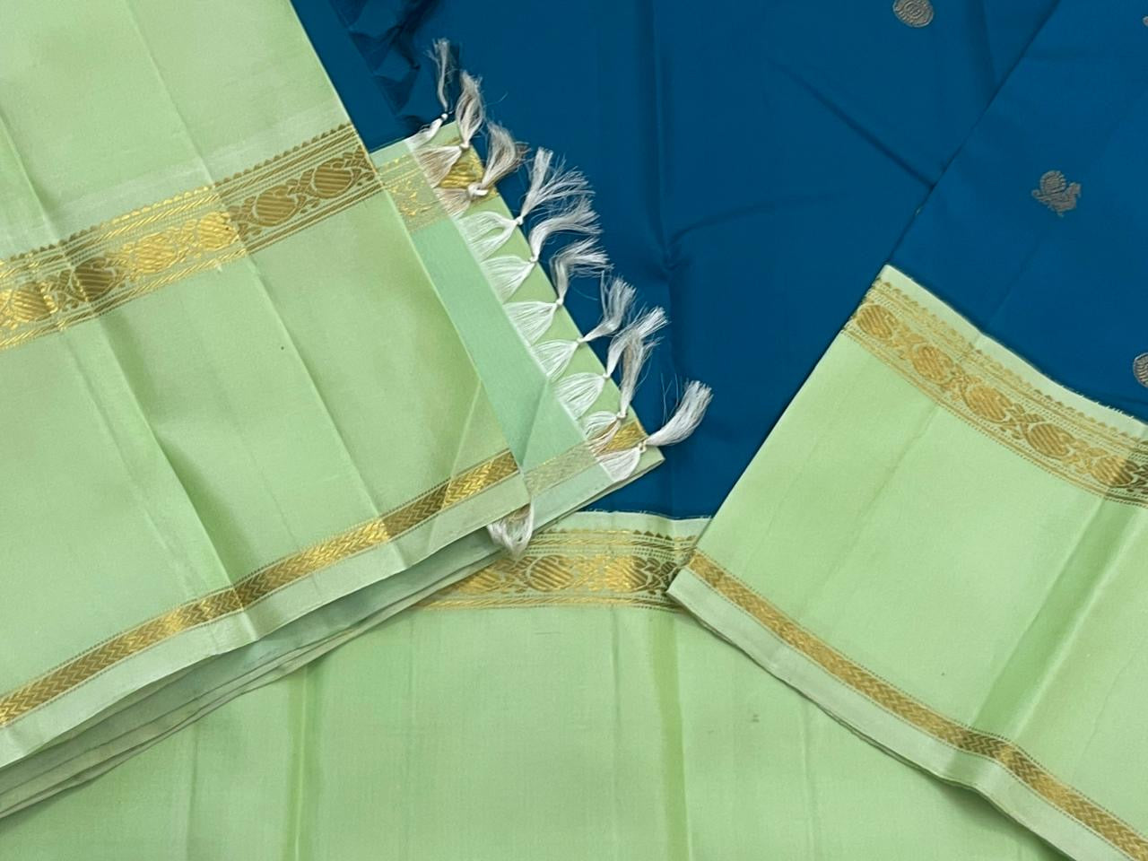 Vasantha Neelam — Teal Korvai Kanchipuram Pure Silk Saree
Peacock-blue body with gold muthu buttas · Mint-pistachio korvai border & pallū
Handloom Kanchipuram • Contrast running blouse included
Silk Mark Certified
Free Shipping within USA, 2 weeks
