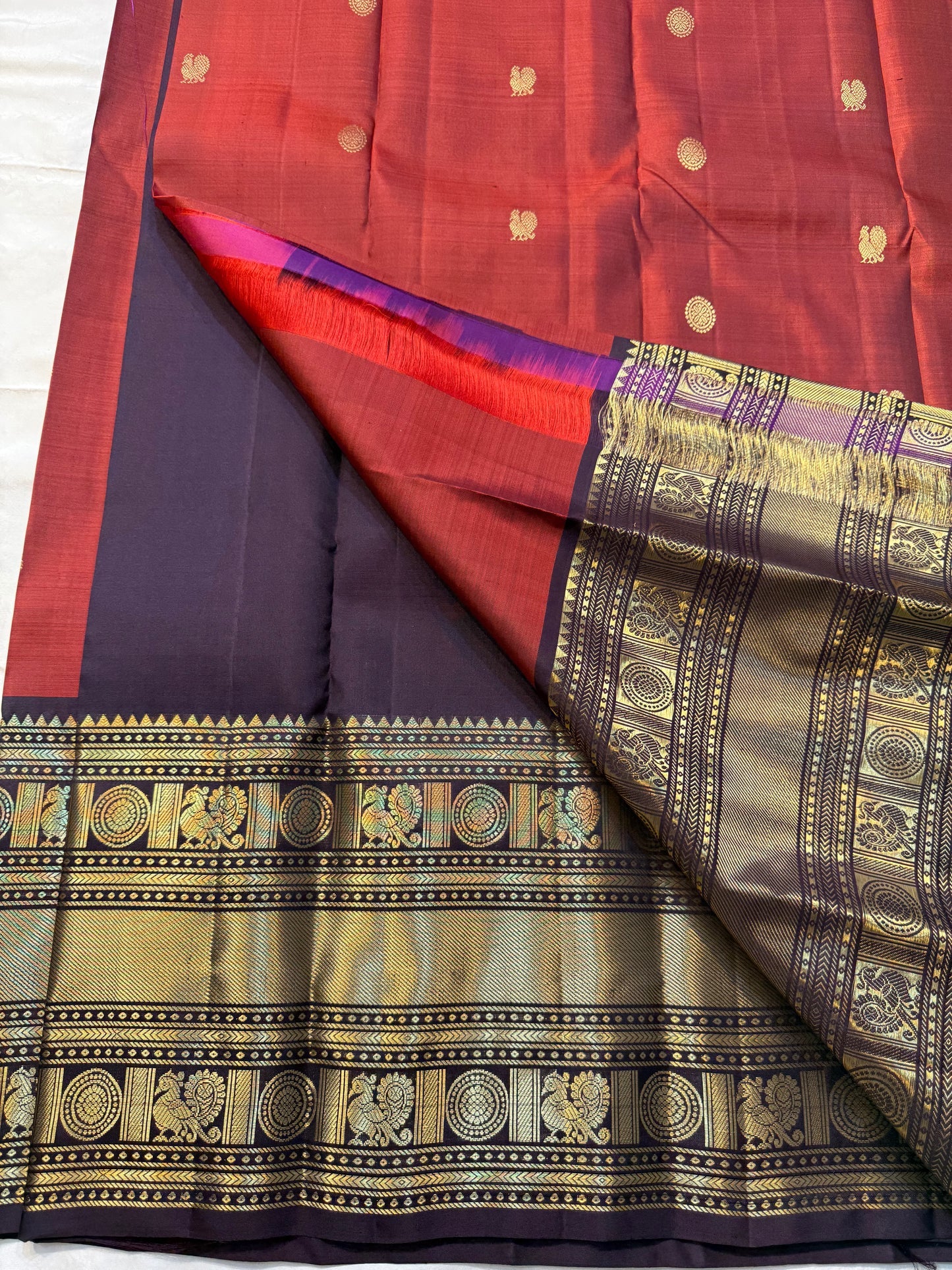 Aruna Mayil – Pure Korvai Kanchipuram Silk Saree
Brick red body with zari rosette buttas
Grand coffee-brown korvai border & pallu with peacock panels, medallions & temple teeth in rich gold zari
Silk Mark Certified | Blouse Piece Included | Fall & Pico