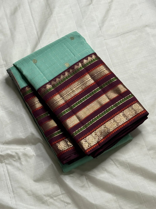 Teal Mint Muthu Kattam — Pure Silk Kanchipuram Saree
Teal-mint body with tiny  zari  buttas & plum-maroon korvai borders
Silk Mark Certified • Free USA Shipping • Ships in Two Weeks