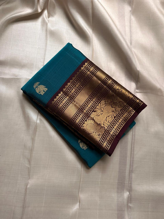 Neeli Megham – Pure Silk Kanchipuram
Teal-blue body with gold annapakshi buttas & aubergine korvai border in antique zari brocade
Silk Mark Certified • Fall & Pico Done • Blouse Stitching Available ($30) • Free Shipping within USA • Ships in Two Weeks