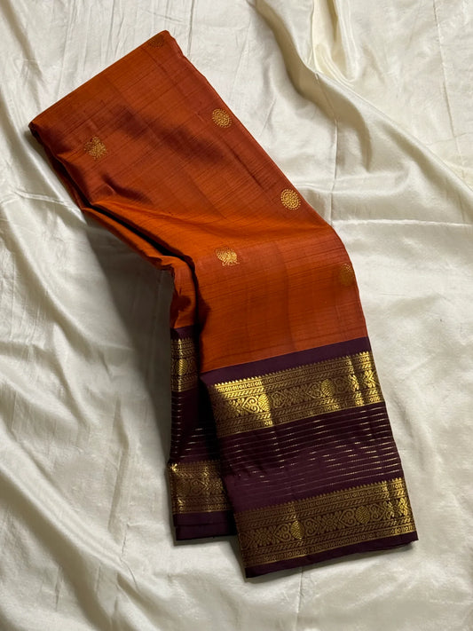 🧡 
Swarnamala — Korvai Kanchipuram Pure Silk
Rust-orange body with radiant gold chakram buttas
Deep purple korvai borders with rich zari detailing
Striped zari brocade pallu with temple-inspired motifs
Silk Mark Certified • Free Shipping within USA