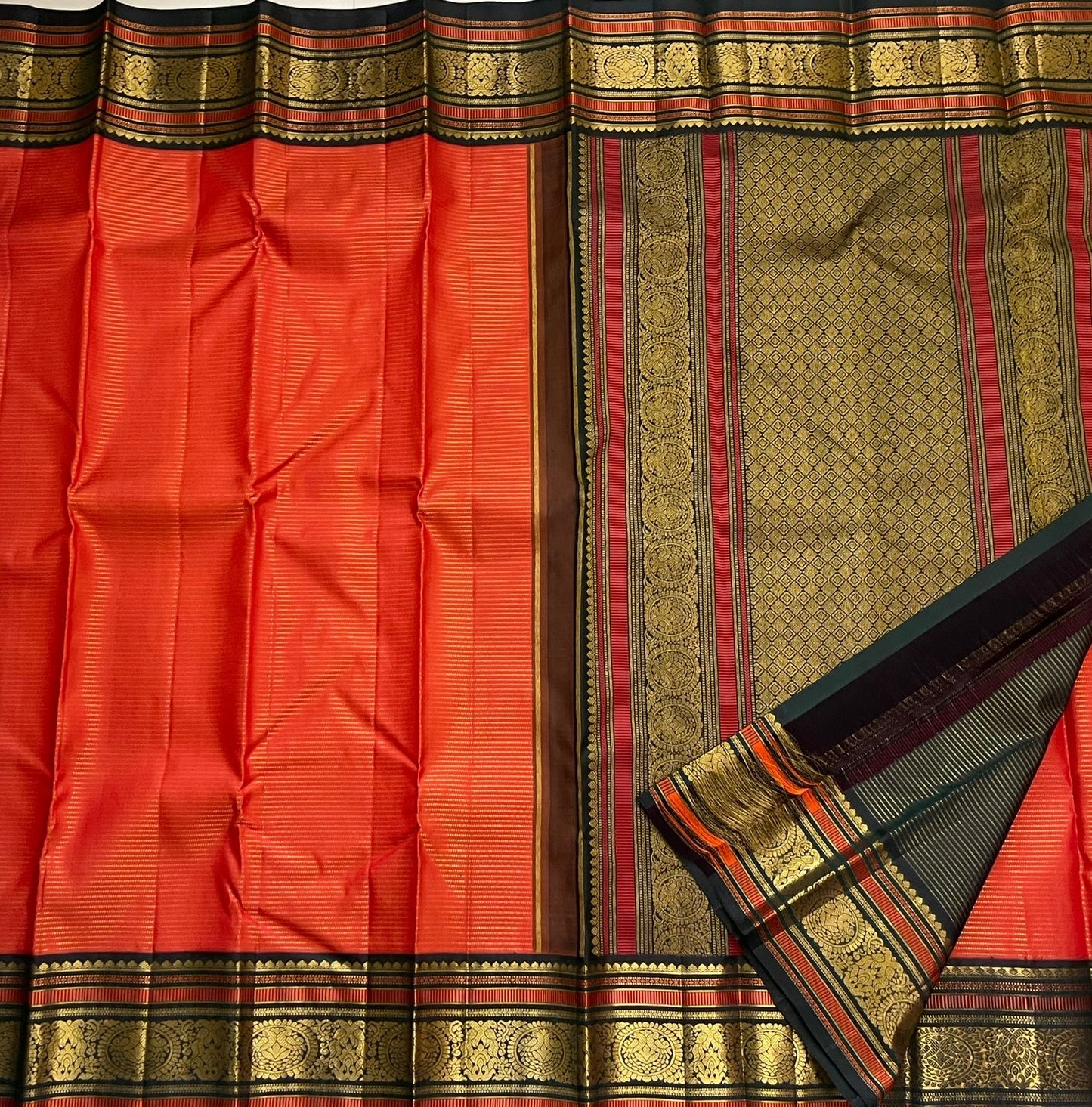 Aruna Mayil Chakram
Pure Kanchipuram Silk Saree – Reddish-Orange Body with Gold Zari Chakram Buttas
Contrast Bottle Green Korvai Borders with Mayil & Temple Motifs
Grand Zari Pallu with Diamond Brocade Weave & Hand-Knotted Tassels
Silk Mark Certified ✅ |