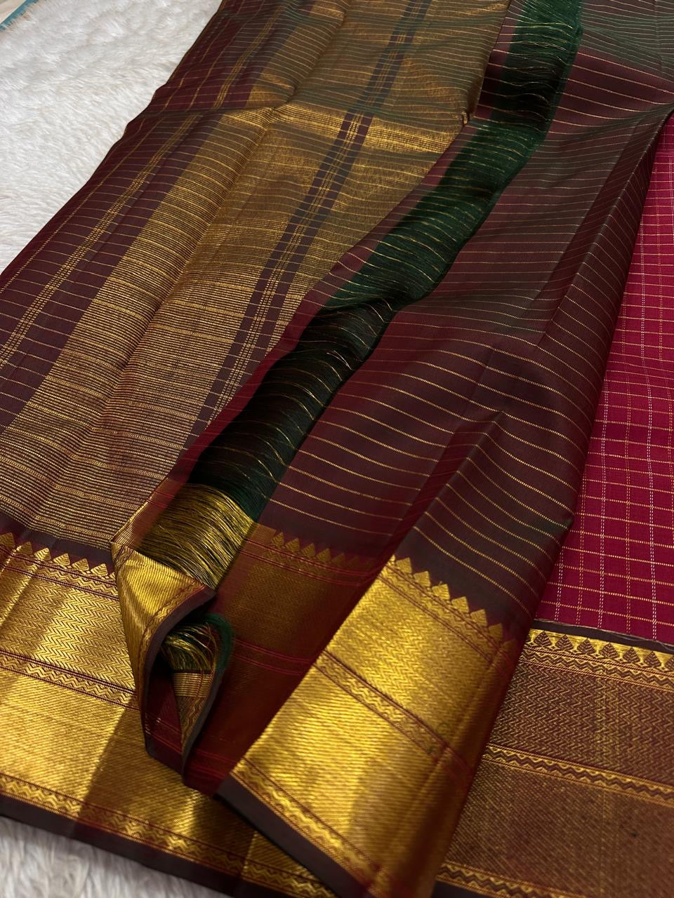 Ruby Zari Kattam – Pure Kanchipuram Silk Saree
Rich Ruby Red Body with Gold Zari Checks
Broad Golden Border with Maroon Highlights & Temple Motifs
Dual-Toned Maroon-Green Pallu with Intricate Zari Weaves
Silk Mark Certified, delivery in 2 weeks