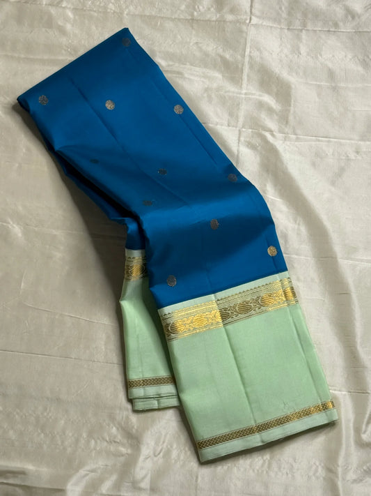 Vasantha Neelam — Teal Korvai Kanchipuram Pure Silk Saree
Peacock-blue body with gold muthu buttas · Mint-pistachio korvai border & pallū
Handloom Kanchipuram • Contrast running blouse included
Silk Mark Certified
Free Shipping within USA, 2 weeks