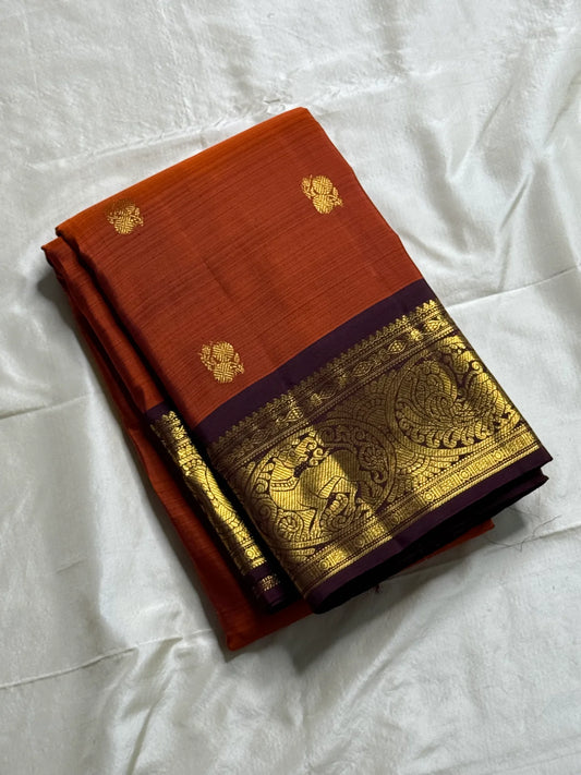 Rust Orange & Wine Korvai – Pure Kanchipuram Silk Saree
Burnt rust-orange shot body with dainty gold paisley buttas
Deep wine korvai borders in antique gold—Annapakshi & Yaali medallions
Grand wine pallu with full-zari jaal & temple panels
Silk Mark