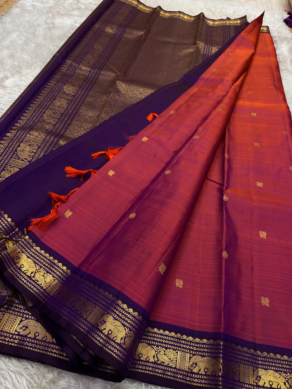 Anju ✨ – Red & Rust-Orange Shot Kanchipuram Pure Silk Saree
with Majestic Elephant & Peacock Motifs
Regal Deep Purple Korvai Contrast Border
Opulent Gold Zari Brocade Pallu