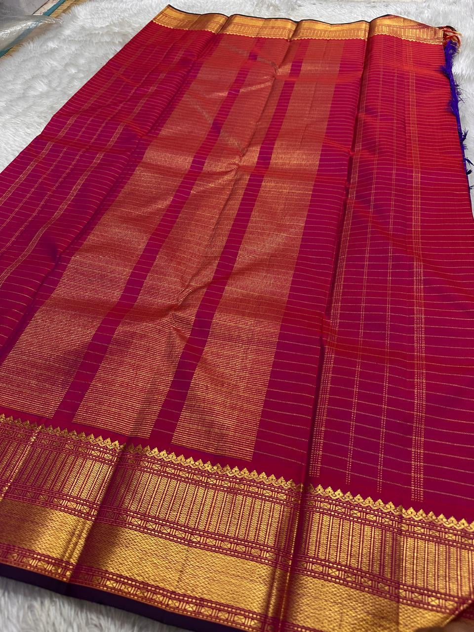 Amethyst Zari Kattam – Pure Kanchipuram Silk Saree
Rich Amethyst Purple Body with Golden Zari Checks
Broad Gold Zari Border with Red Highlights & Temple Motifs
Radiant Ruby Red-Orange Pallu with Lustrous Zari Stripes
Silk Mark Certified, delivery in 2 we