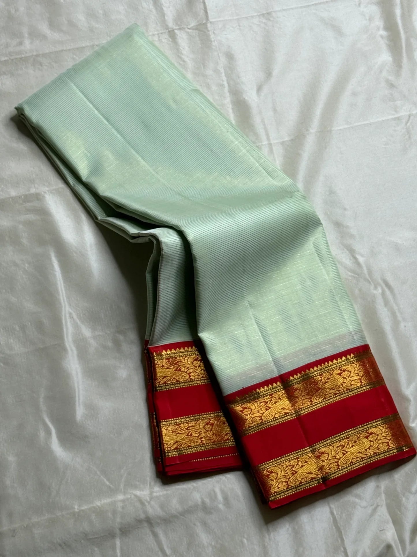 Scarlet Mist ✨ – Pastel Mint Vairaoosi Kanchipuram Pure Silk Saree
Korvai Scarlet-Red Border with Rich Zari Vines & Green Selvedge
Grand Red Pallu with Traditional Bird Buttas & Brocade Panels
Contrast Red Blouse fabric