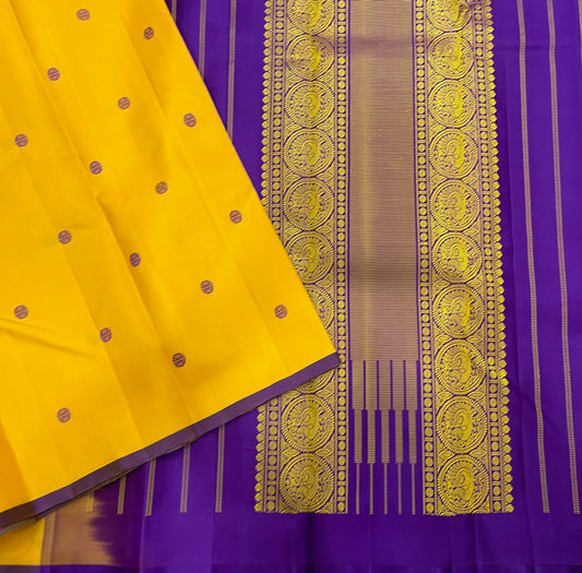 Manjal Vadamalli Chakram – Pure Kanchipuram Silk Saree
Marigold yellow body with purple floral thread buttas
Grand royal purple pallu with gold medallion zari & reku-style stripes
Handwoven Double Warp Weave | Silk Mark Certified | Fall & Pico Done