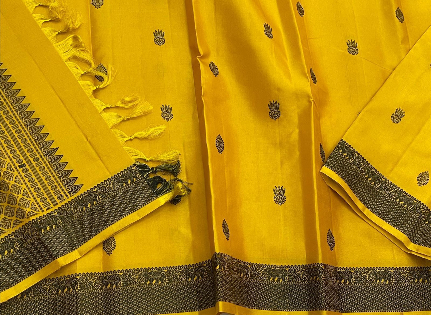 Marigold – Pure Kanchipuram Silk Saree
Haldi yellow body with charcoal paisley buttas
Contrast charcoal border in silk thread, floral vine
Silk Mark Certified | Blouse Piece Included | Fall & Pico Done
Free Shipping within USA | Ships in 2 Weeks