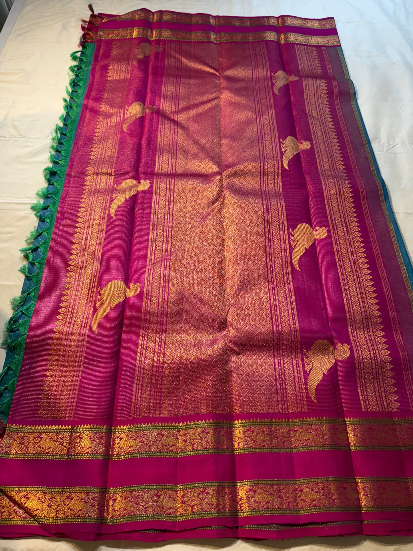 Kavi ✨ – Pure Kanchipuram Silk Saree
Teal Blue Silk Body with Lustrous Shot Weave
Rich Magenta Contrast Border in Gold Zari
Grand Pallu with Intricate Kili (Parrot) Motifs
Magenta Blouse with Matching Zari Border Silk Mark Certified, delivery in 2 weeks