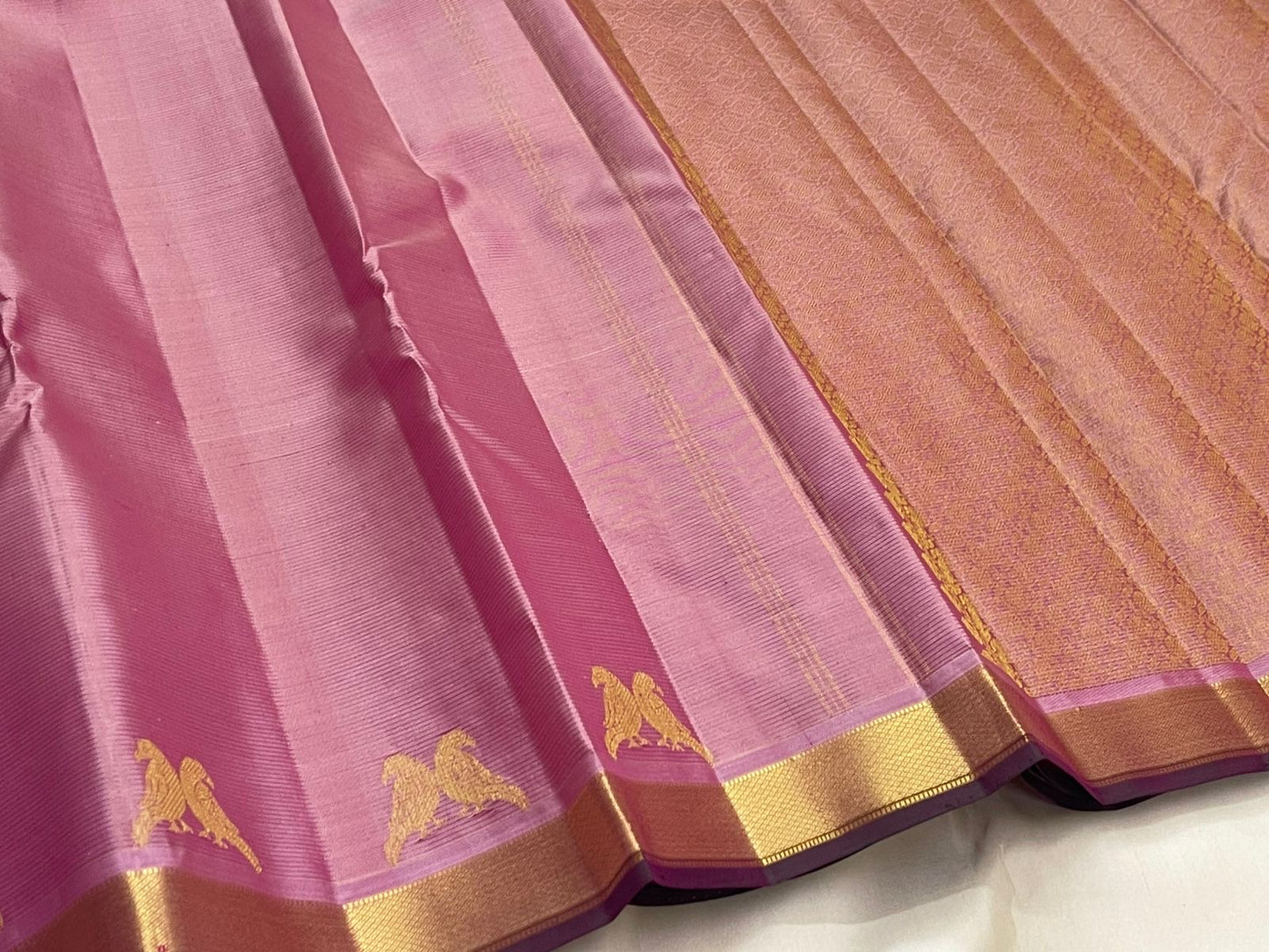 Pastel pink pure Kanchipuram silk saree featuring traditional gold zari kili motifs along the border and classic silk texture