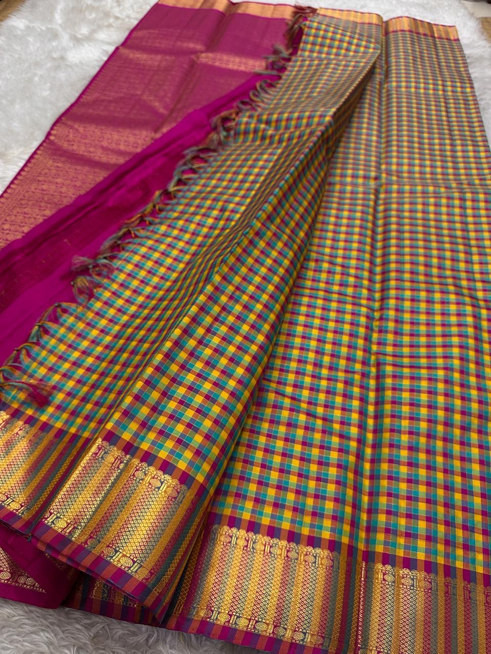 A classic Kanchipuram in Pattani Kattam checks with green, magenta, mustard, and cream.
Finished with a contrast pink border and pallu.
Paisley and chakram motifs in a graceful grid add timeless charm.
