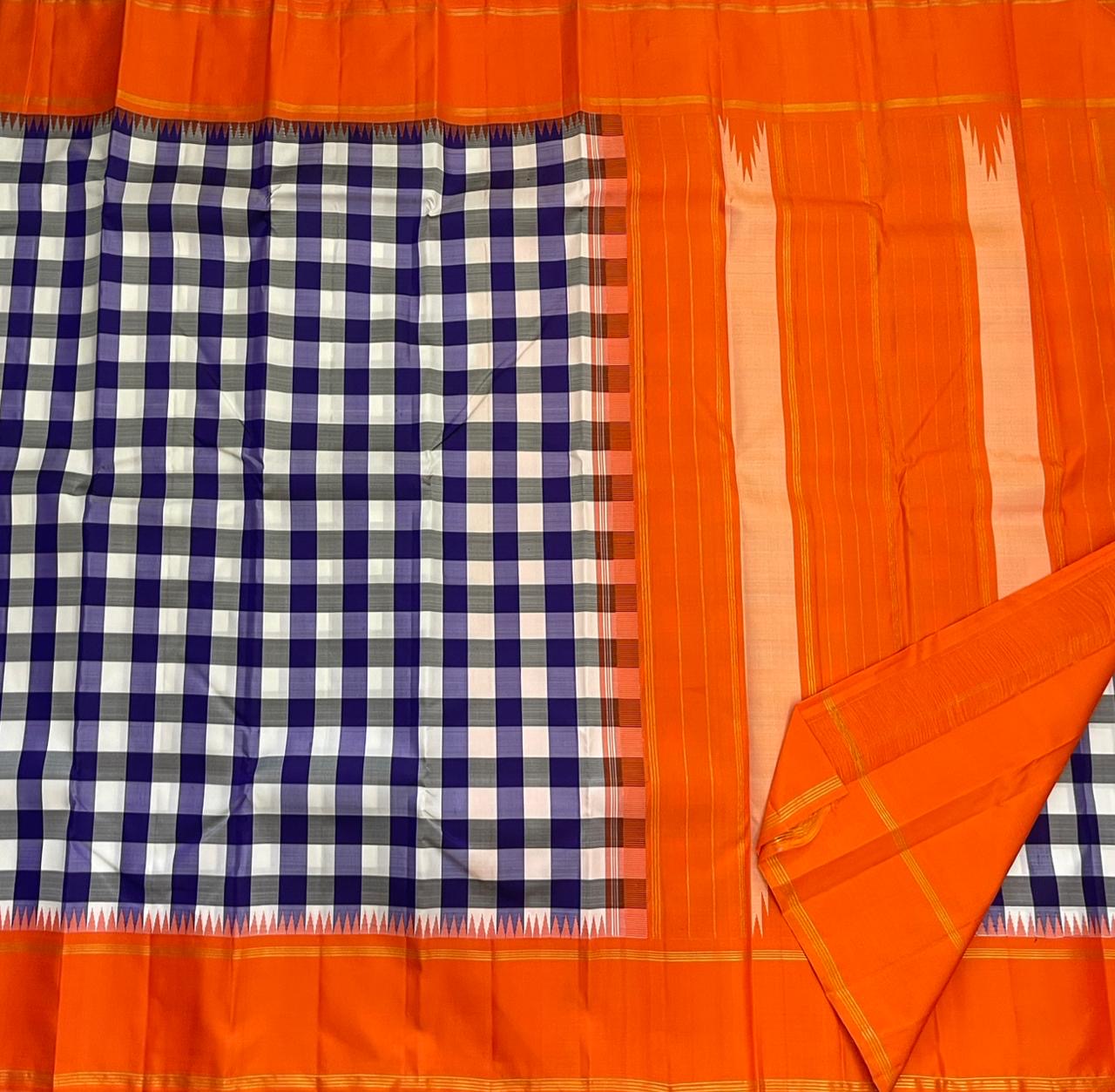 Indigo–Tangerine Checkmate — Pure Silk Kanchipuram
Bold indigo–lilac–white buffalo checks with ash accents ✨
Vibrant tangerine korvai border with temple (reku) teeth 🌸
Solid tangerine pallu with fine thread stripes & tassels 🪔
Silk Mark Certified •