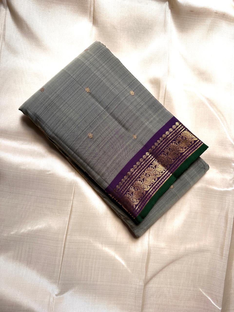 Dove Gray Mayuri — Pure Kanchipuram Silk Saree ✨
Soft dove-gray body with gold coin buttas, violet borders & emerald selvedge 💜
Silk Mark Certified ✅ | ships in two weeks