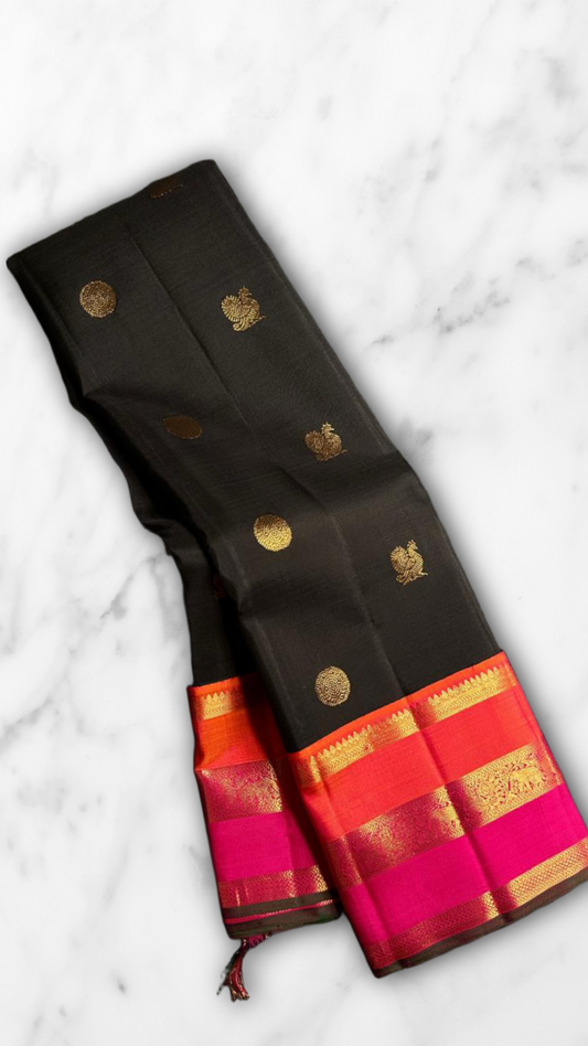 Kanmani — Black & Rani Pure Silk Kanchipuram Saree
Inky black body with gold medallion & peacock buttas
Striking rani-pink and kavi-orange korvai borders with temple-edge zari
Rich rani-pink brocade pallu with grid jaal & heritage vines
Silk Mark Cert