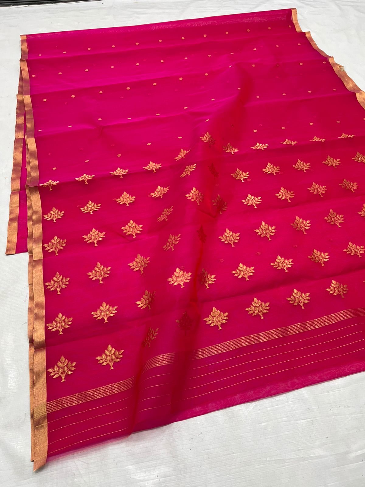 A timeless classic, this Rani pink Chanderi silk saree is a celebration of heritage and elegance. Crafted from lightweight silk with a luxurious sheen, the saree features all-over gold zari floral leafy buttas