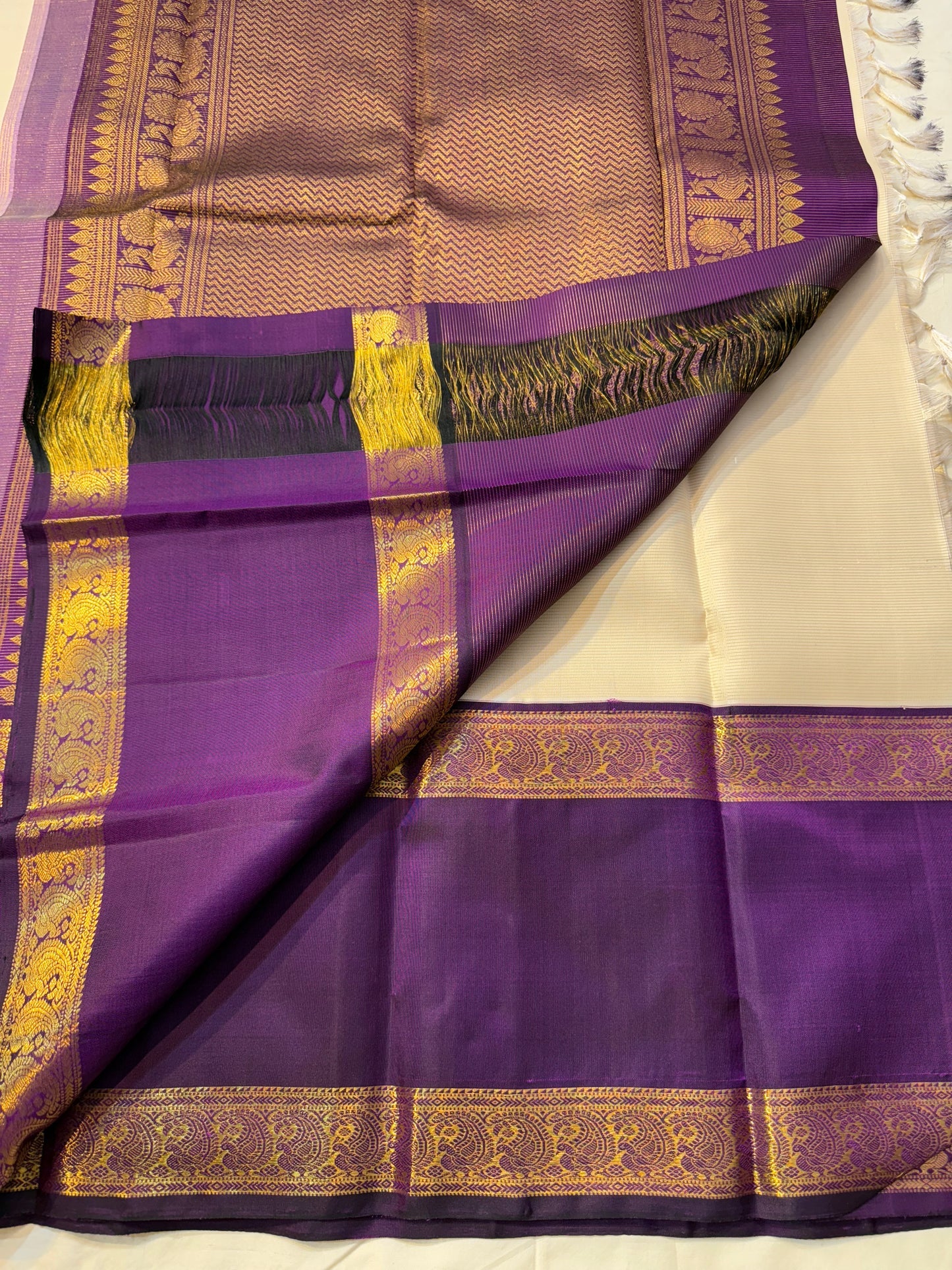 Ivory Violet Vairaoosi — Pure Silk Kanchipuram Saree
Pearl-Ivory Vairaoosi Body with Gold Round Buttas ✨
Deep Violet Korvai Border & Chevron Zari Pallu • Silk Mark Certified • Free USA Shipping • ships in 2 weeks