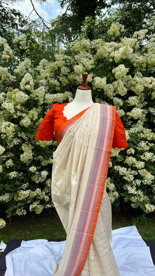 Tamara – Ivory Cream Semi-Silk Saree with Vibrant Orange Border
Paired with a Scallop Neck & Sleeve Ready-to-Wear Orange Blouse (Size 36–42)