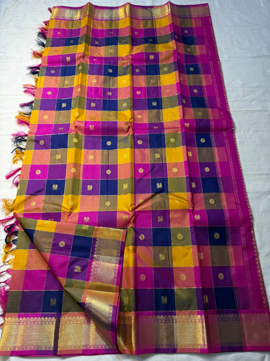 Navaranga Kattam — Multi-Color Paalum pazhamum checks  Kanchipuram Pure Silk
Rani-magenta contrast border & rich zari pallū 
Gold coin & peacock buttas over jewel-tone squares
Handloom Kanchipuram • Matching magenta blouse with borders
