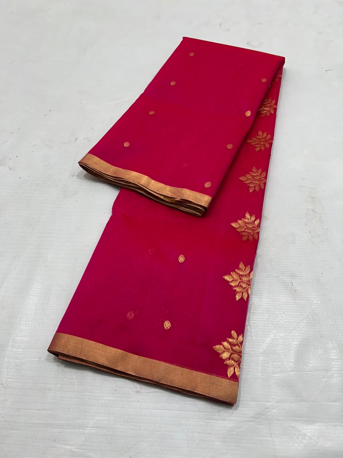 A timeless classic, this Rani pink Chanderi silk saree is a celebration of heritage and elegance. Crafted from lightweight silk with a luxurious sheen, the saree features all-over gold zari floral leafy buttas