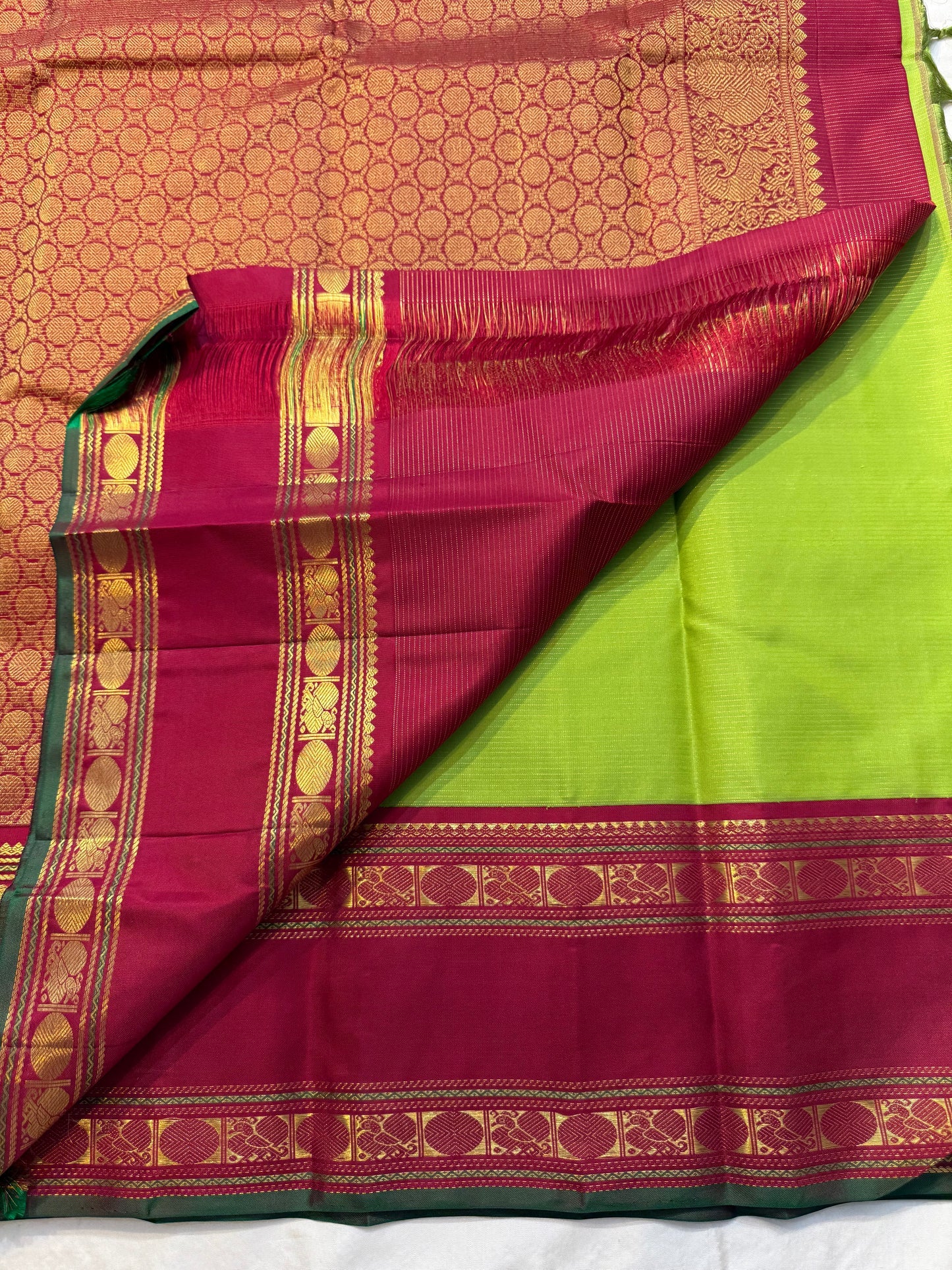 Maavilai Arakku Chakram — Korvai Kanchipuram Pure Silk
Parrot-green vaira-oosi body with soft pin-stripe sheen
Contrast arakku/rani border with gold chakram medallions & temple motifs
Arakku pallu with all-over coin-jaal; contrast blouse included