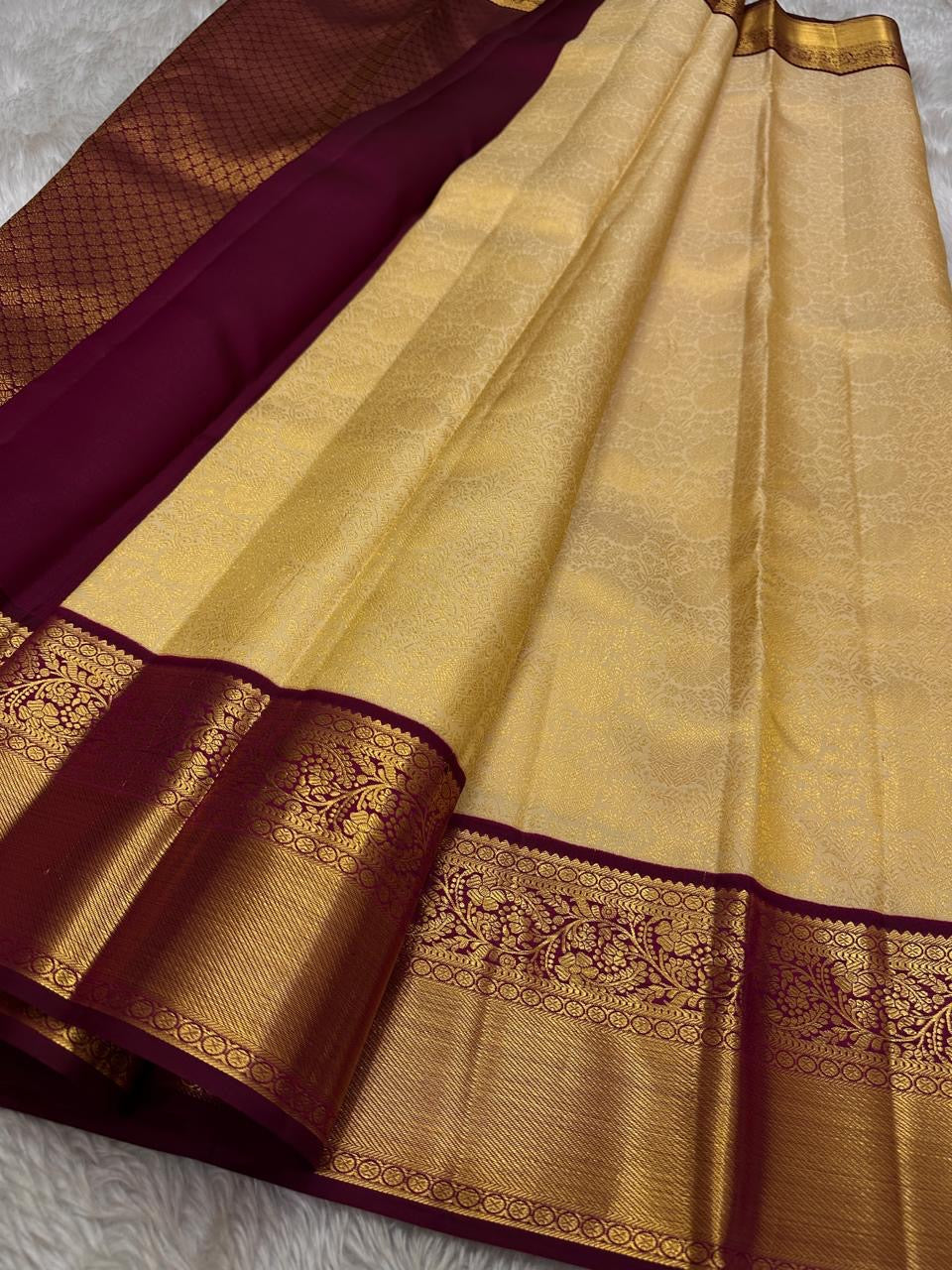 Ragini – Ivory & Gold Kanchipuram Pure Silk Saree with Floral Jaal & Maroon Baavanji Border
Timeless elegance shines through the delicate ivory base and shimmering gold zari floral jaal. The rich maroon Baavanji border and intricate pallu details complete