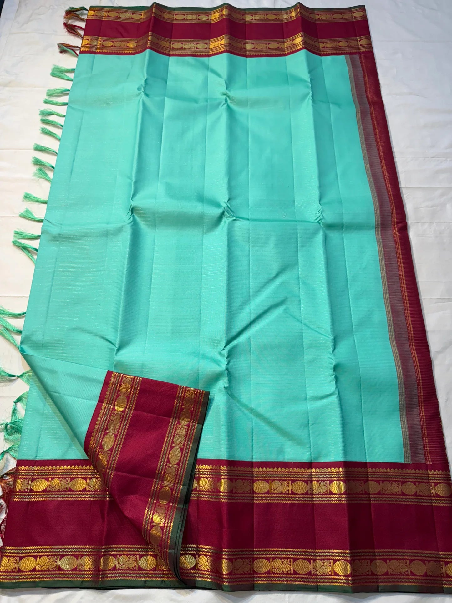 Neer Pachai Vairaoosi — Kanchipuram Pure Silk saree 
Sea-foam/aqua body with classic Vairaoosi pinstripes
Contrast ruby-maroon korvai borders with gold chakram & floral panels
Grand maroon pallu with all-over chakram jaal and paisley vines; aqua tassel