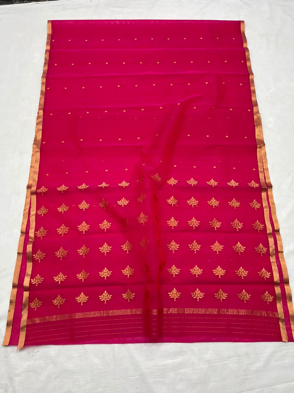 A timeless classic, this Rani pink Chanderi silk saree is a celebration of heritage and elegance. Crafted from lightweight silk with a luxurious sheen, the saree features all-over gold zari floral leafy buttas