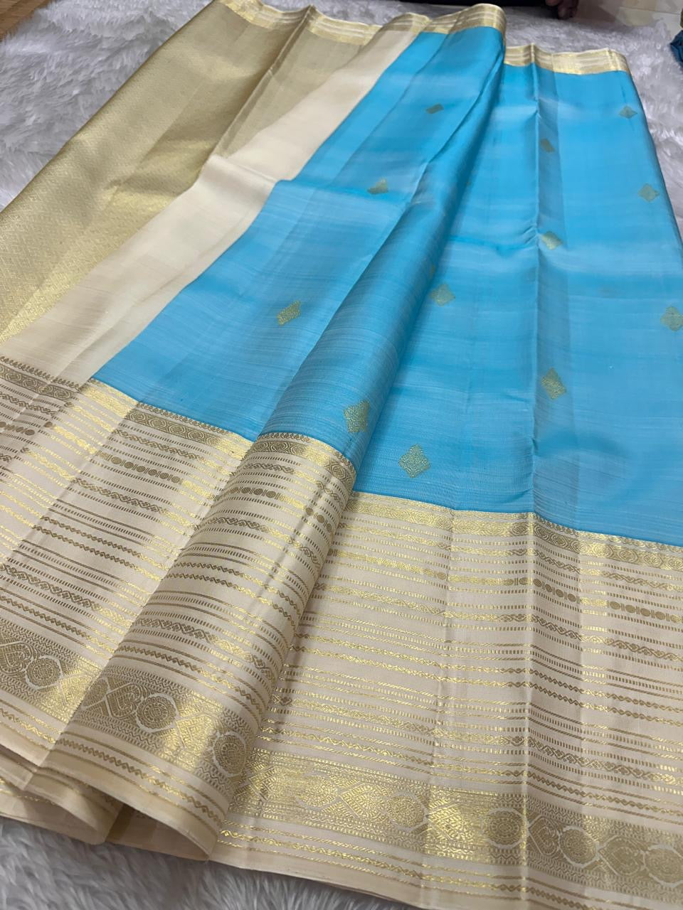 Blue Vennila Varisai – Pure Kanchipuram Silk Saree
Blue body with gold leaf buttas; contrast ivory varisai borders
Grand ivory pallu with rich zari stripes; contrast ivory blouse
Silk Mark Certified | Blouse Piece Included | Fall & Pico Done
Free Shipping