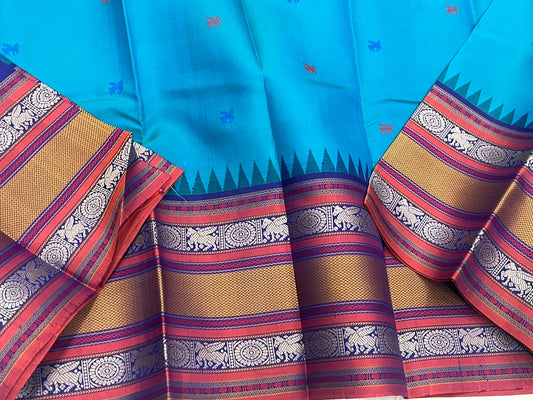 Peacock-teal body with woven silk-thread buttas in navy & coral hues
Korvai contrast ruby-maroon borders with gaja-chakram & temple motifs
Grand varisaipettu striped pallu in navy, mustard & maroon tones
Silk Mark Certified • Ships in Two Weeks