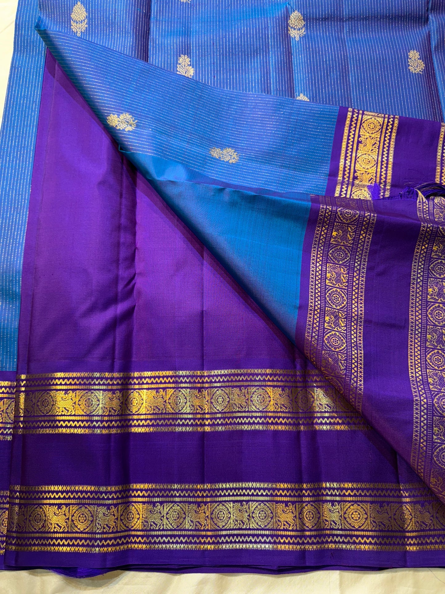 Azure Blue Purple Horizon – Neelam blue body with royal-purple korvai borders  Pure Kanchipuram silk • manga (paisley) buttas + fine pin-stripes  Opulent purple brocade pallu • contrast blouse with zari border  Silk Mark Certified | Fall & Pico Done |