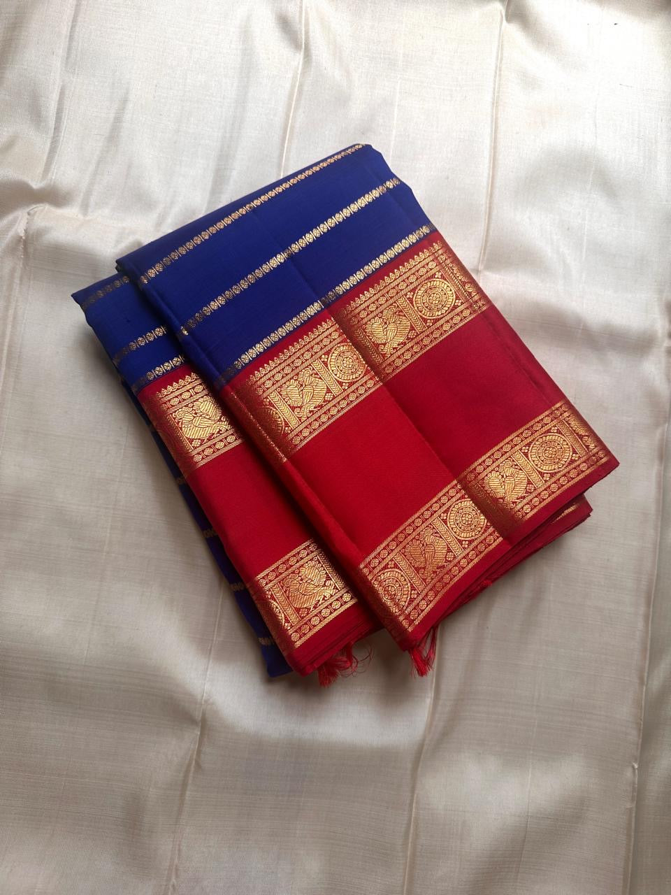 Meera – A Living Raga in Kanchipuram Silk: Draped in Crimson and Iconic MS Blue, Adorned with Gold Zari Seer, Muthu Borders, and Peacocks and kamalam , Woven in the Spirit of Classical Grace and Devotion
