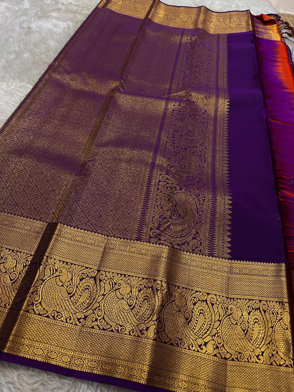 Aubergine Amber Kattam – Pure Kanchipuram Silk Saree
Deep Aubergine Purple Body with Gold Kattam Checks
Grand Zari Borders with Majestic Peacock Motifs
Contrast Amber-Orange Pallu with Rich Zari Detailing
Silk Mark Certified | ships in two weeks