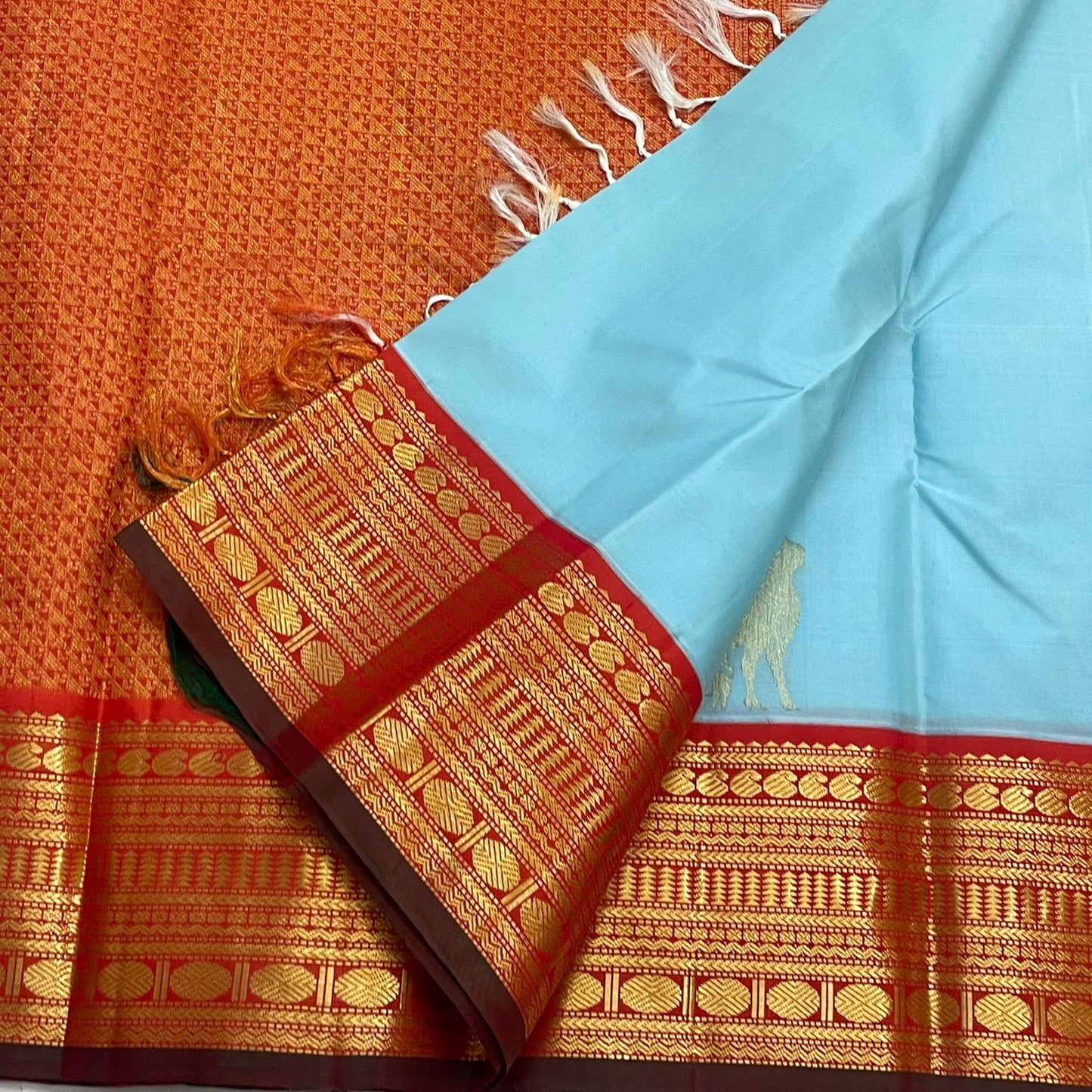 Kamadhenu — Pure Silk Kanchipuram
Sky-blue body with gold Kamadhenu motifs, fiery-orange pallu & ruby-red korvai borders ✨
Silk Mark Certified • Antique Zari Weave • Ships in Two Weeks • Free Shipping within USA