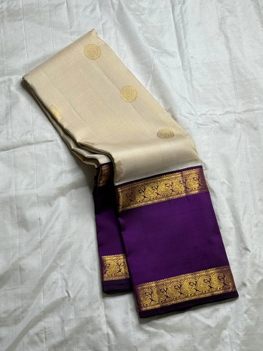 Ivory Violet Vairaoosi — Pure Silk Kanchipuram Saree
Pearl-Ivory Vairaoosi Body with Gold Round Buttas ✨
Deep Violet Korvai Border & Chevron Zari Pallu • Silk Mark Certified • Free USA Shipping • ships in 2 weeks