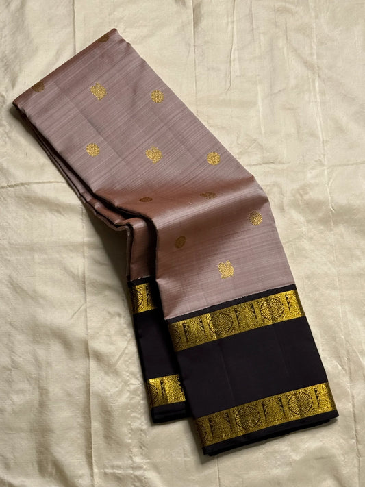 Ash Rose Butta — Pure Silk Kanchipuram
• Dusty ash-rose body with gold buttas
• Inky-black broad borders with antique-gold zari
• Black contrast pallu with zari stripe panels & tassels
• Silk Mark Certified • Ships in Two Weeks • Free Shipping within