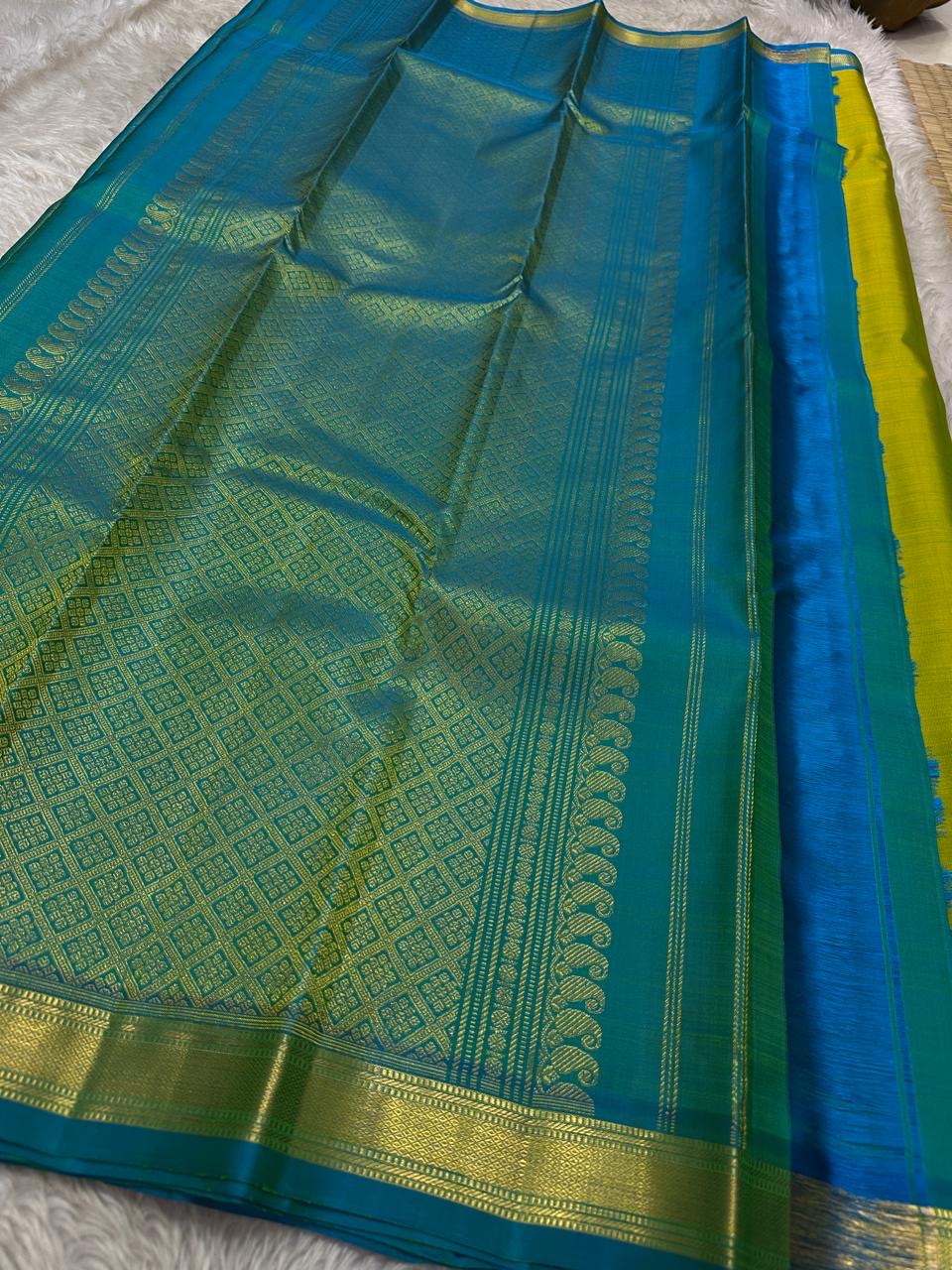 Citrus and Teal – Pure Kanchipuram Silk Saree
Dual-tone body in parrot green and turmeric.
Elegant gold leaf buttas across the drape.
Teal korvai border
Rich teal pallu with diamond jaal and temple motifs.
Silk Mark Certified, delivery in 2 weeks