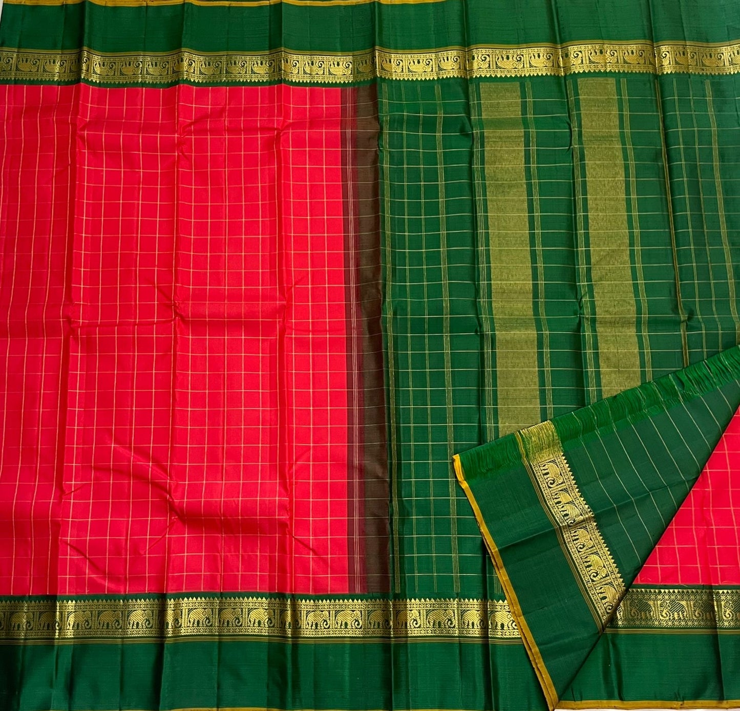 Emerald Ruby Korvai
Pure Kanchipuram Silk Saree – Ruby Red Body with muthu kattam Grid Checks
Emerald Green Korvai Borders Adorned with Zari Elephant Motifs
Grand Green Zari seer Pallu with Traditional motifs
Silk mark certified, ships in 2 weeks