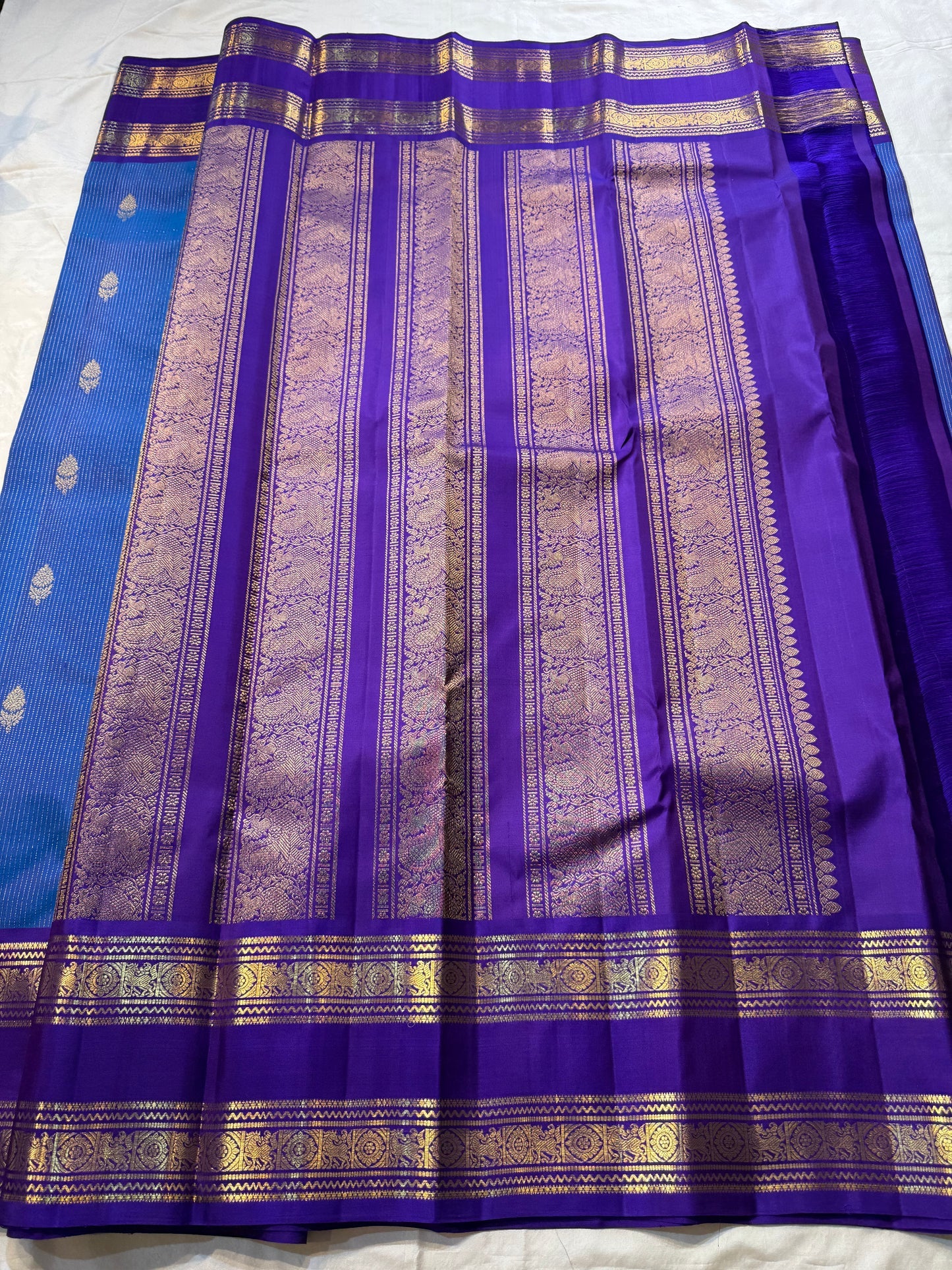 Azure Blue Purple Horizon – Neelam blue body with royal-purple korvai borders  Pure Kanchipuram silk • manga (paisley) buttas + fine pin-stripes  Opulent purple brocade pallu • contrast blouse with zari border  Silk Mark Certified | Fall & Pico Done |