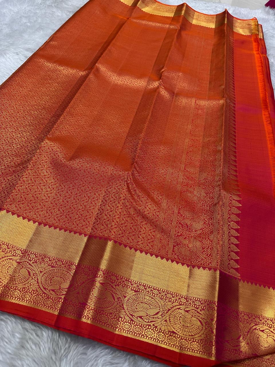 Agnika – Tomato orange shot Red Kanchipuram Silk Saree with Mayil Chakram Butta & Orange Border
Fiery and regal, Agnika is a pure Kanchipuram silk saree featuring a rich red body adorned with intricate Mayil Chakram buttas.