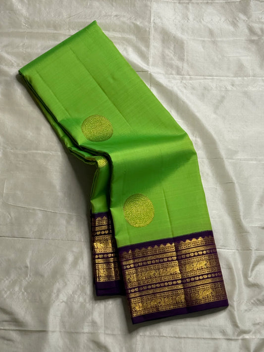 Arangetram — Parrot-Green Kanchipuram Pure Silk
Royal Purple Korvai Border 
Elephant Procession Panels & Coin Buttas
Rich Brocade Pallu • Blouse Included
Silk Mark Certified • Free USA Shipping • Ships in Two Weeks