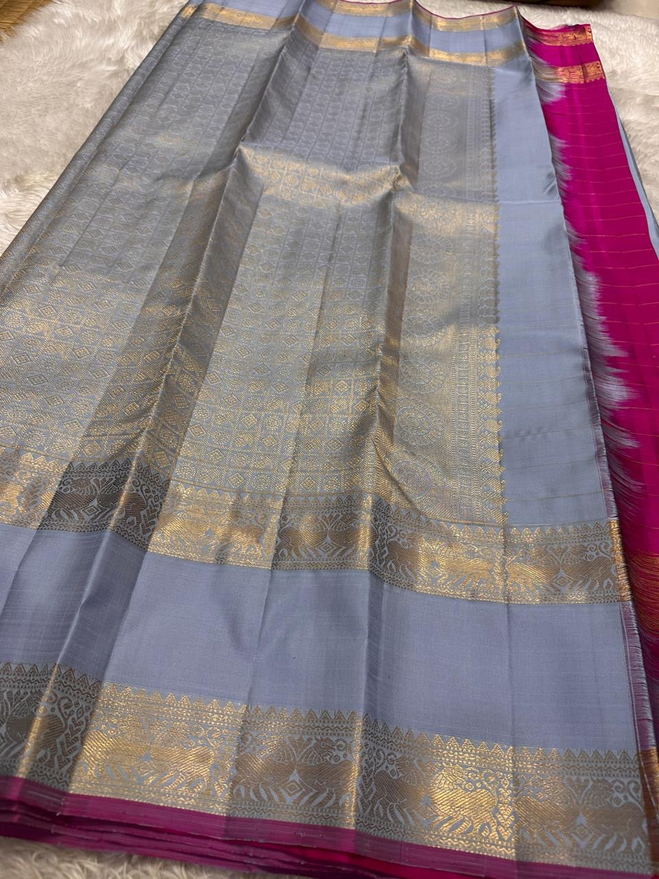 Fuchsia in Sky – Pure Silk Kanchipuram Saree
Sky Blue Body with Gold Kattam Checks & Petite Buttas
Fuchsia Contrast Petni Pallu with Zari Reku Stripes
Wide Gold Zari Border with Peacock & Temple Motifs
Silk mark certified, ships in 2 weeks